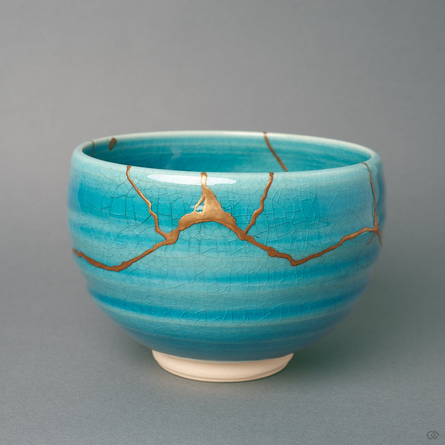 Kintsugi Kyoto matcha bowl in turquoise crackle glaze, gold seams crossing the front, wabi-sabi held in a single vessel.