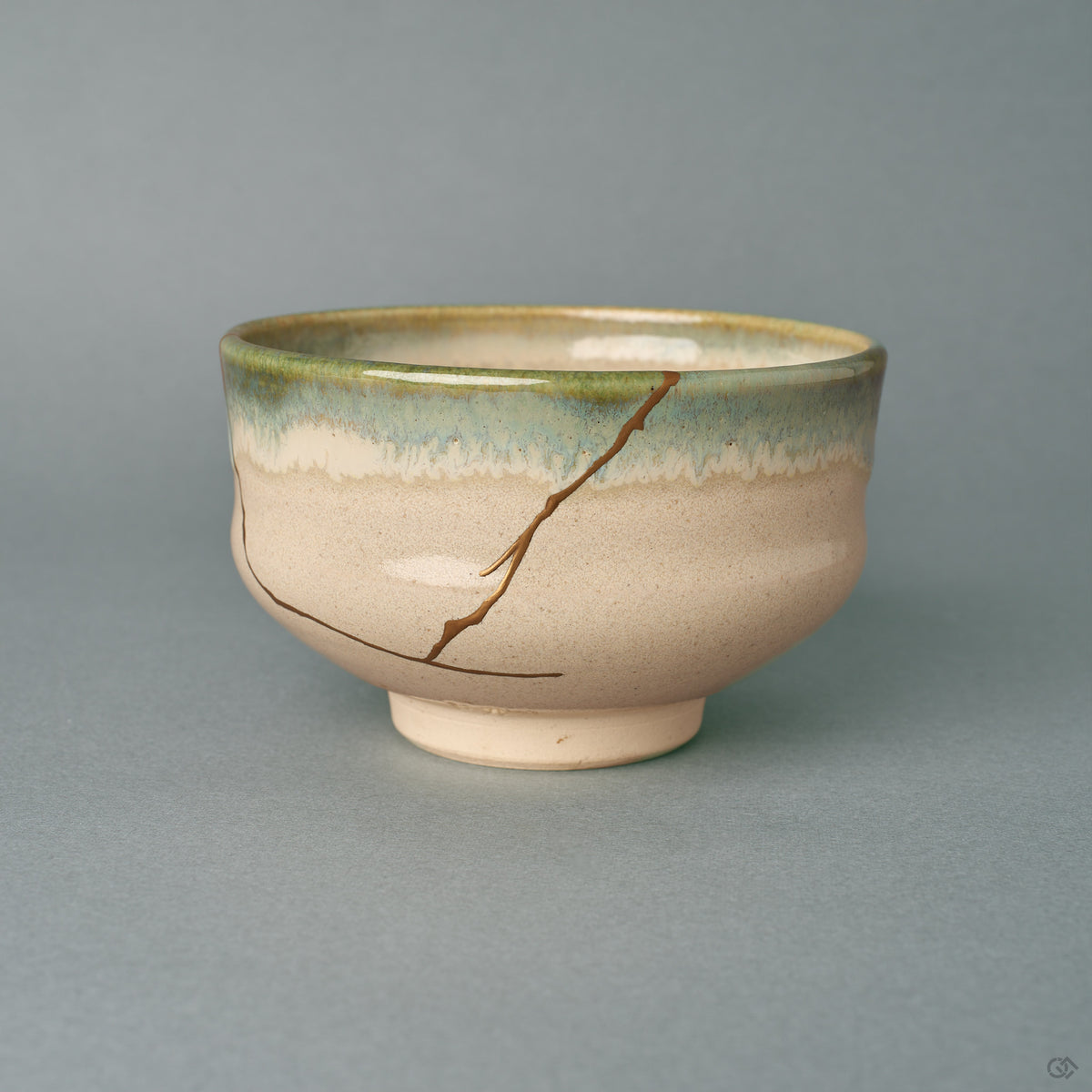 A kintsugi Kyoto Ware matcha bowl seen from the front, its gold seam descending an ivory body beneath a green glaze rim, a quiet beauty.