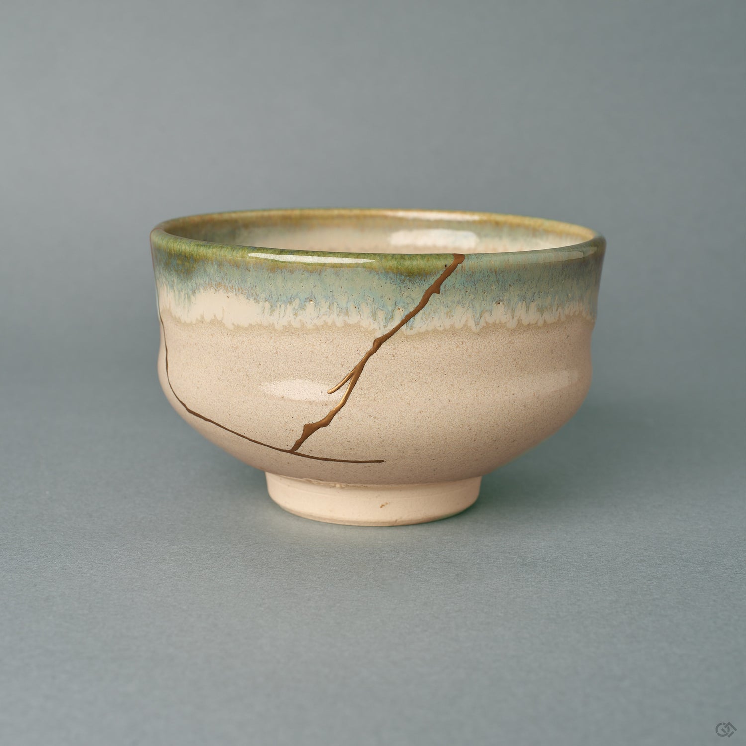 A kintsugi Kyoto Ware matcha bowl seen from the front, its gold seam descending an ivory body beneath a green glaze rim, a quiet beauty.