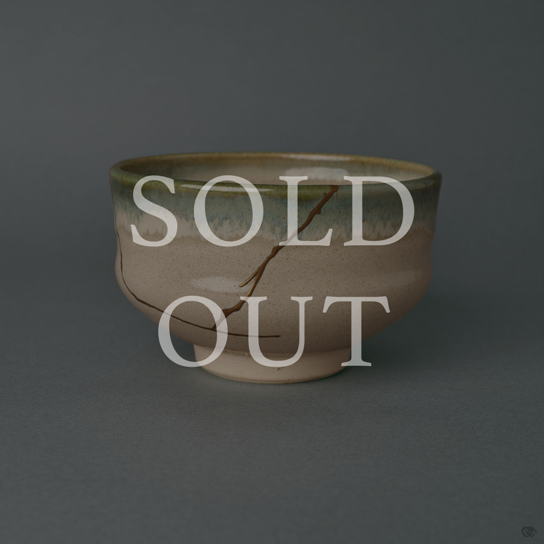 Sold out: kintsugi Kyoto Ware matcha bowl restored with 24K gold, a single gold seam descending an ivory body beneath a green glaze rim.