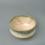 Looking into this kintsugi Kyoto matcha bowl, the glossy cream interior and green-rimmed glaze carry the patina of time.