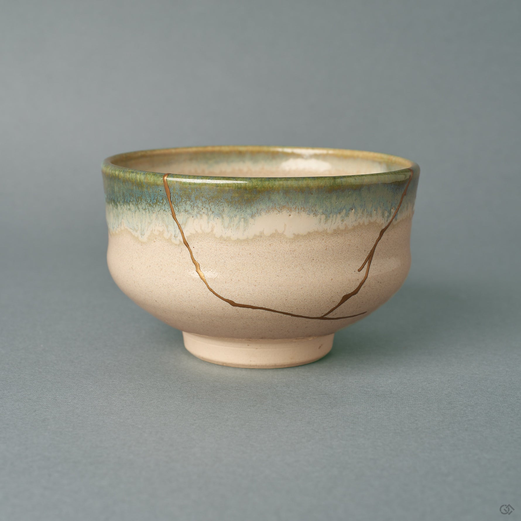 From the side, this kintsugi matcha bowl shows a green-to-blue glaze band wrapping a rounded earthenware form, history made visible in gold.