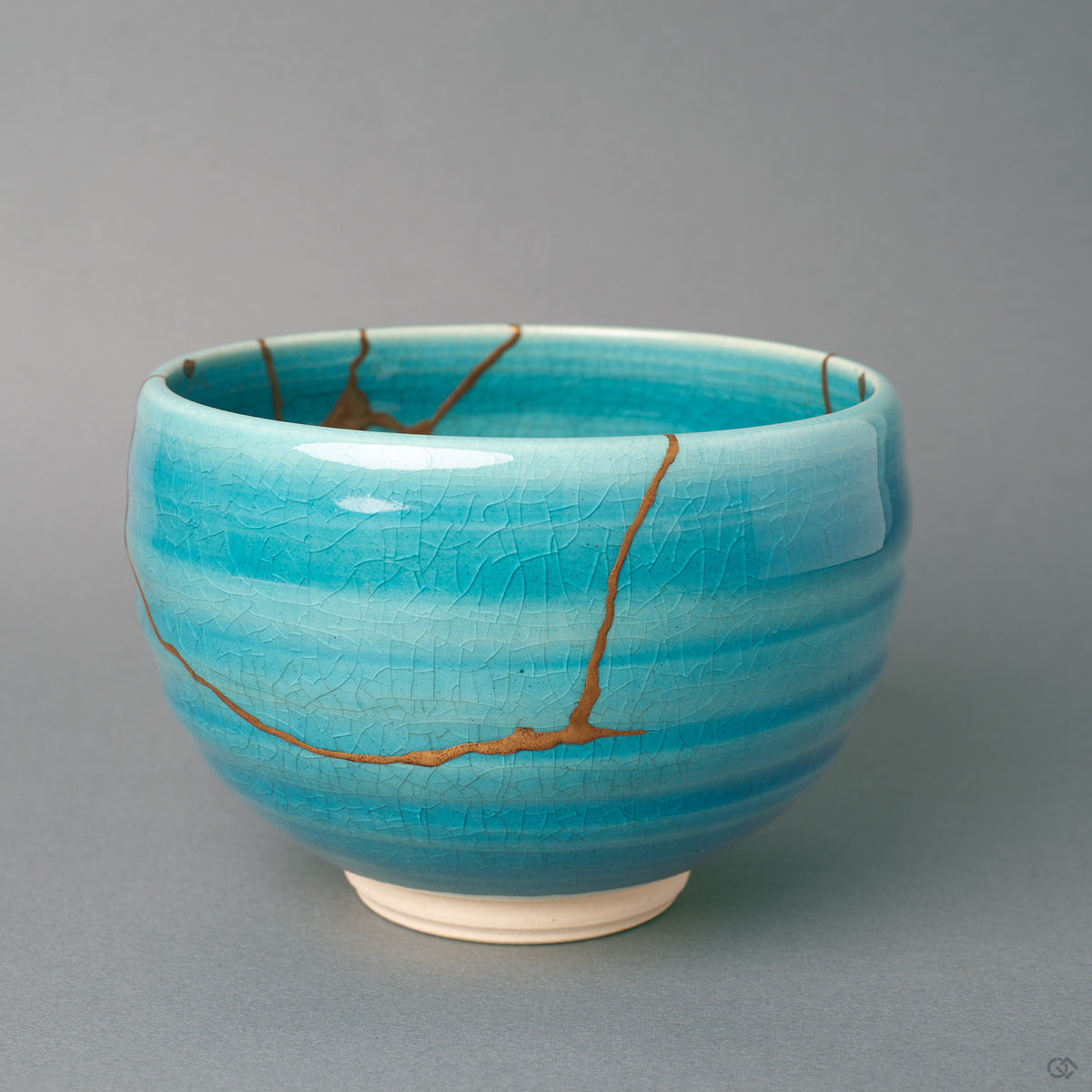 From a third angle, gold kintsugi seams thread around the turquoise glaze, history made visible along the earthenware wall.