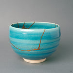 From a third angle, gold kintsugi seams thread around the turquoise glaze, history made visible along the earthenware wall.