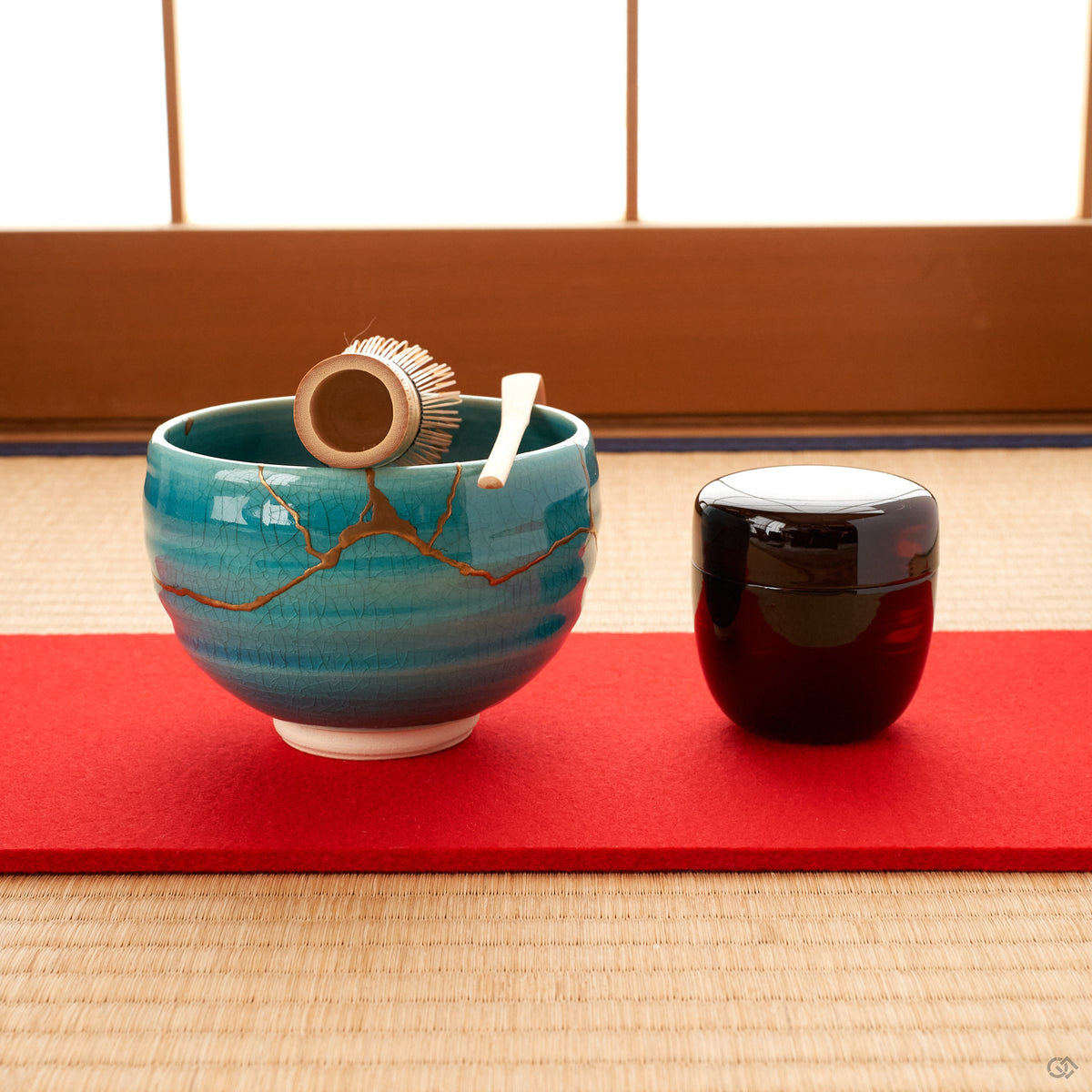 Resting on tatami, the turquoise kintsugi bowl gathers soft light, a moment of contemplation in a quiet room.