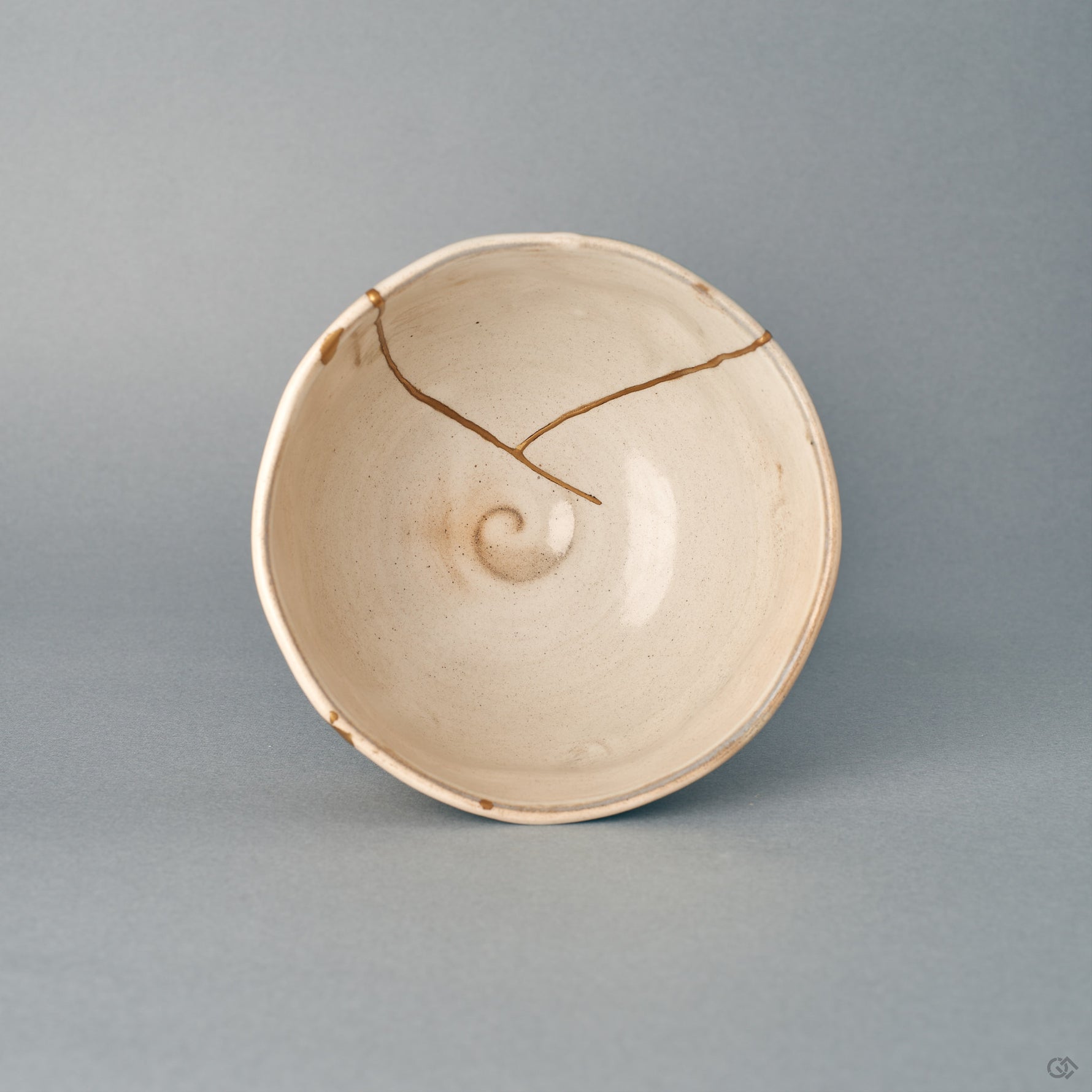 Seen from above, the kintsugi bowl's round mouth frames a cream interior, its carved spirals one-of-a-kind.