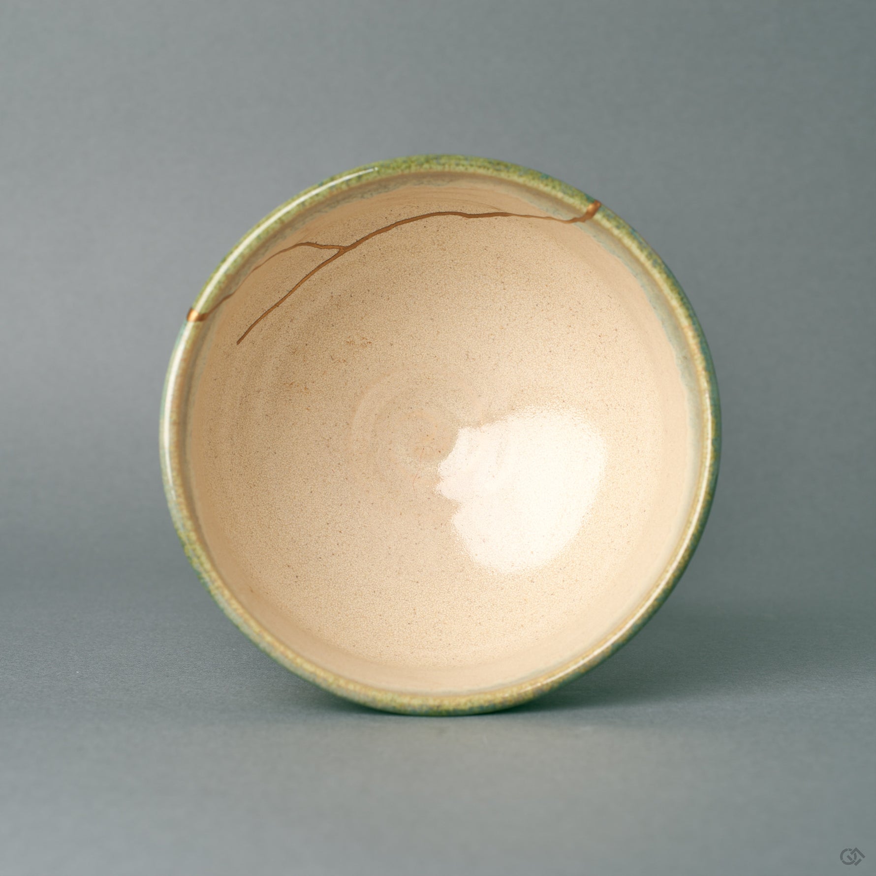 Seen from above, this kintsugi matcha bowl frames its glossy interior with a green glaze rim, the gold seam crossing one edge with wabi-sabi grace.