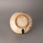 Bottom of a kintsugi Oribe matcha bowl showing the unglazed foot ring and earthenware base, crafted resilience from the kiln to the gold.