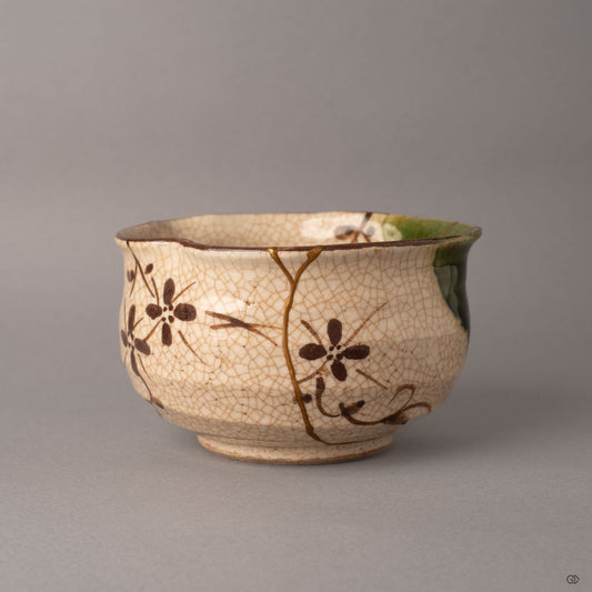 Side view of a kintsugi Oribe earthenware matcha bowl showing the robust hand-thrown form and gold seams over crackled glaze, heritage made visible.