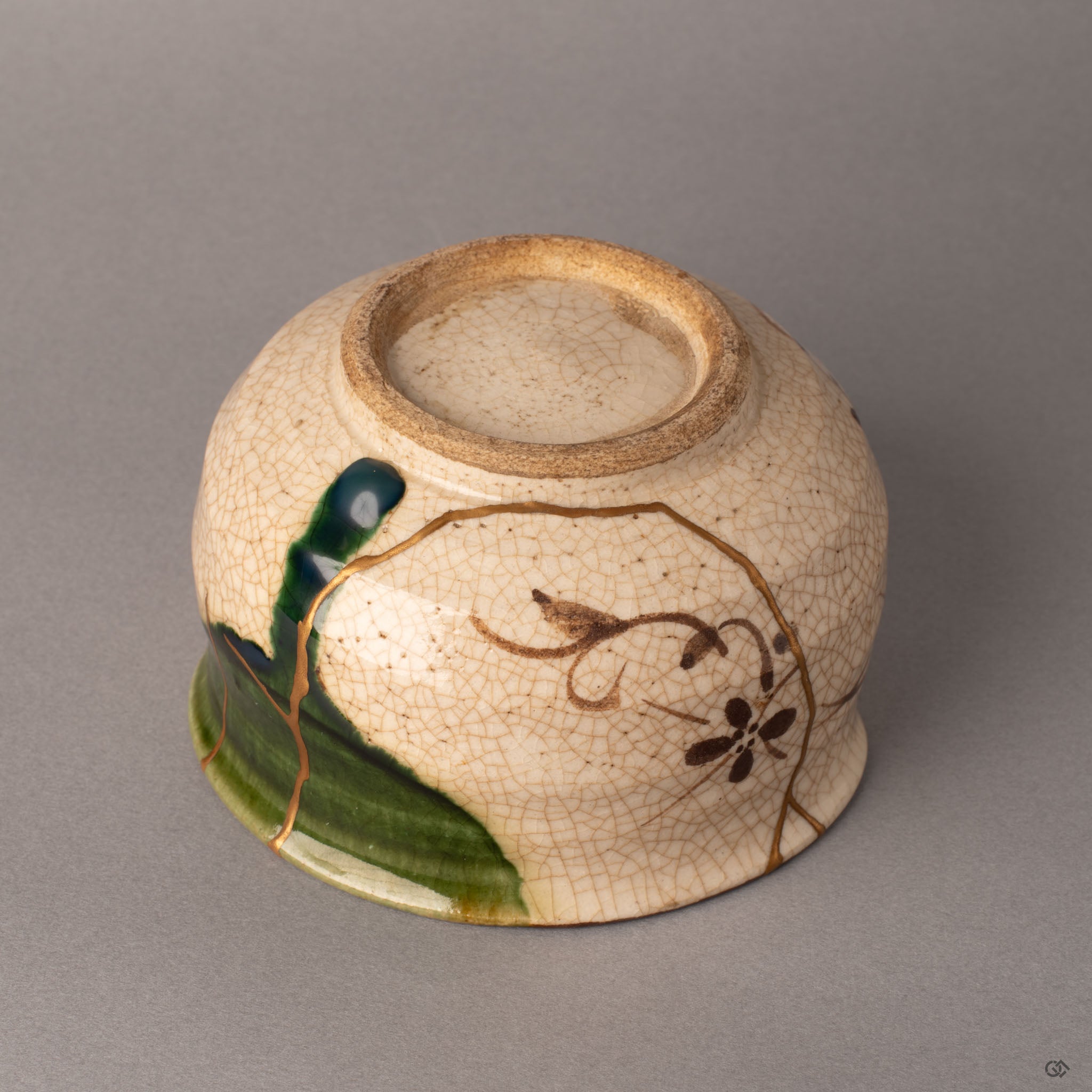 Alternate side of a kintsugi Oribe matcha bowl revealing the botanical motif and gold restoration line along the earthenware body, enduring legacy.