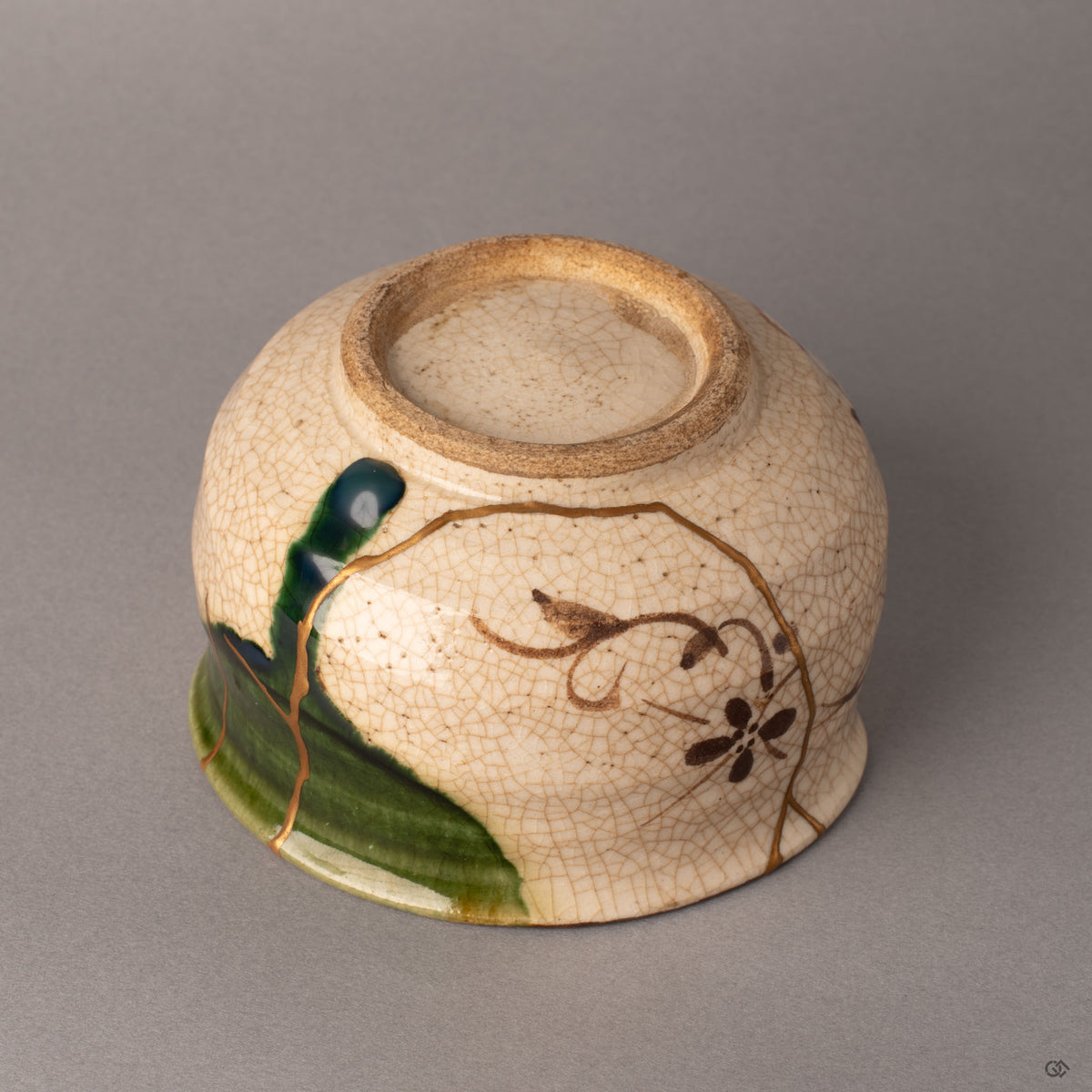 Alternate side of a kintsugi Oribe matcha bowl revealing the botanical motif and gold restoration line along the earthenware body, enduring legacy.