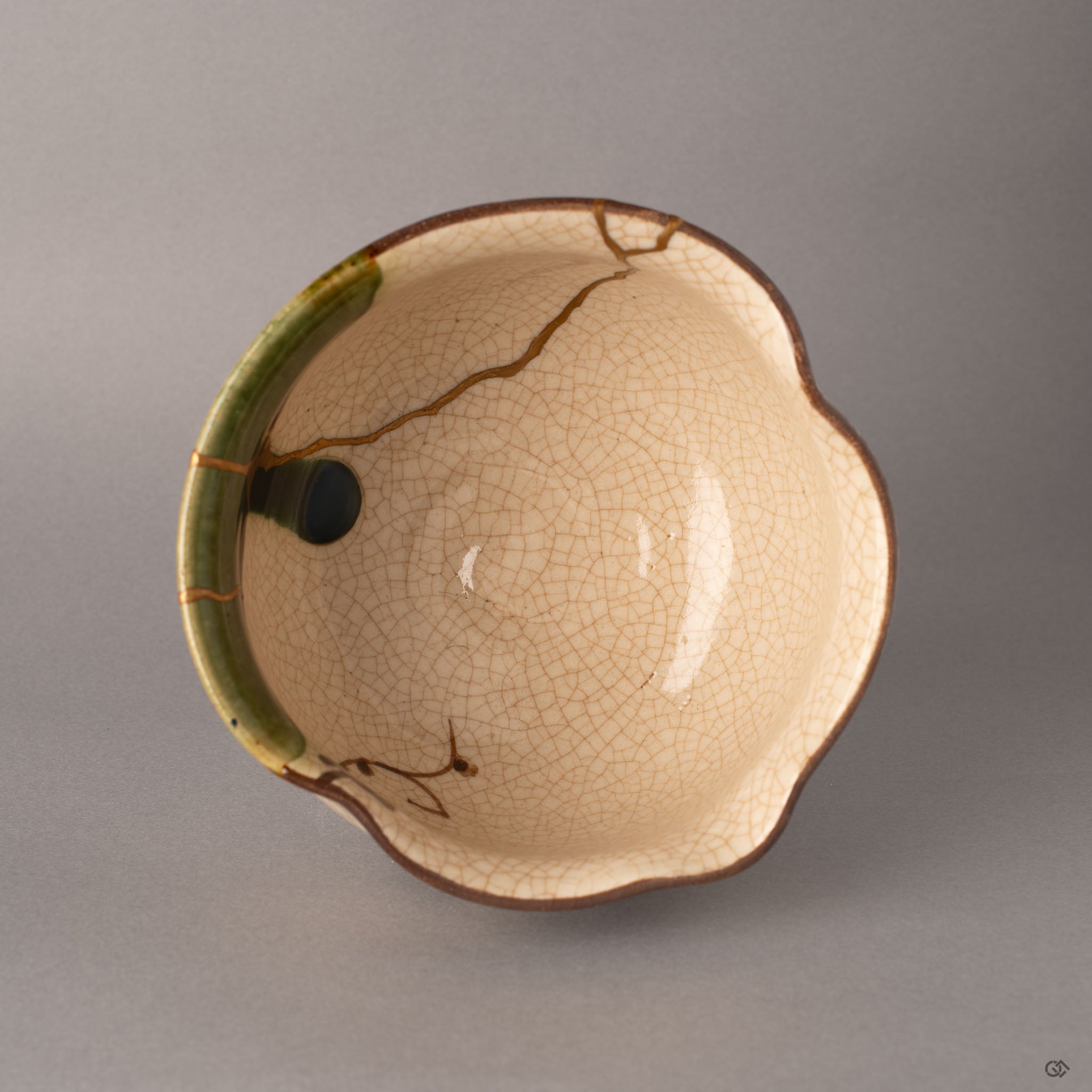 Top view of a kintsugi Oribe ware matcha bowl with the potter's mark visible, gold restoration lines crossing the green-glazed interior.