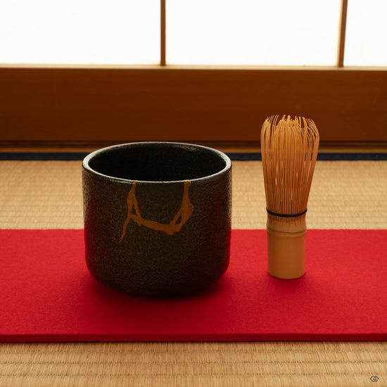 Kintsugi matcha bowl resting on tatami in filtered shoji light, a moment of contemplation in mindful luxury.