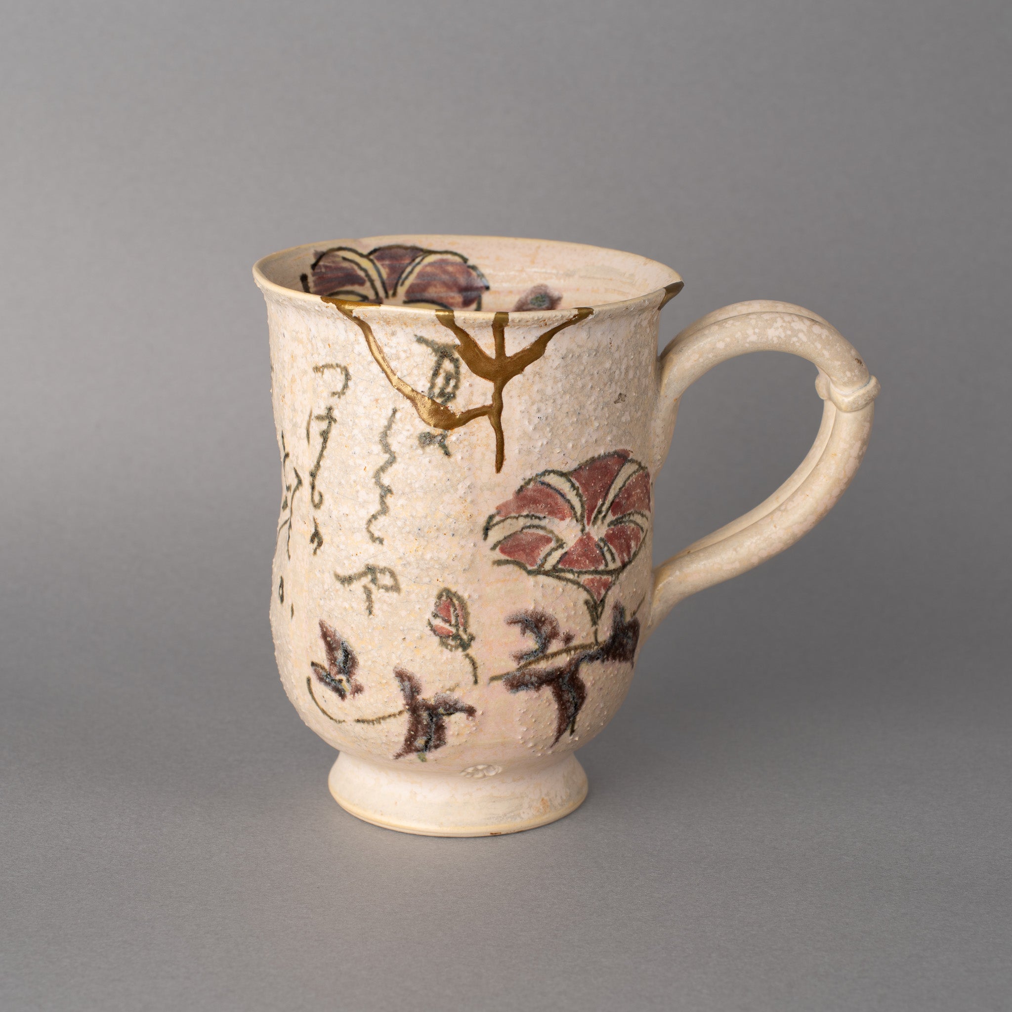 A Kyoto ware mug with kintsugi seams in 24K gold crossing its ceramic surface, wabi-sabi held in an everyday form.