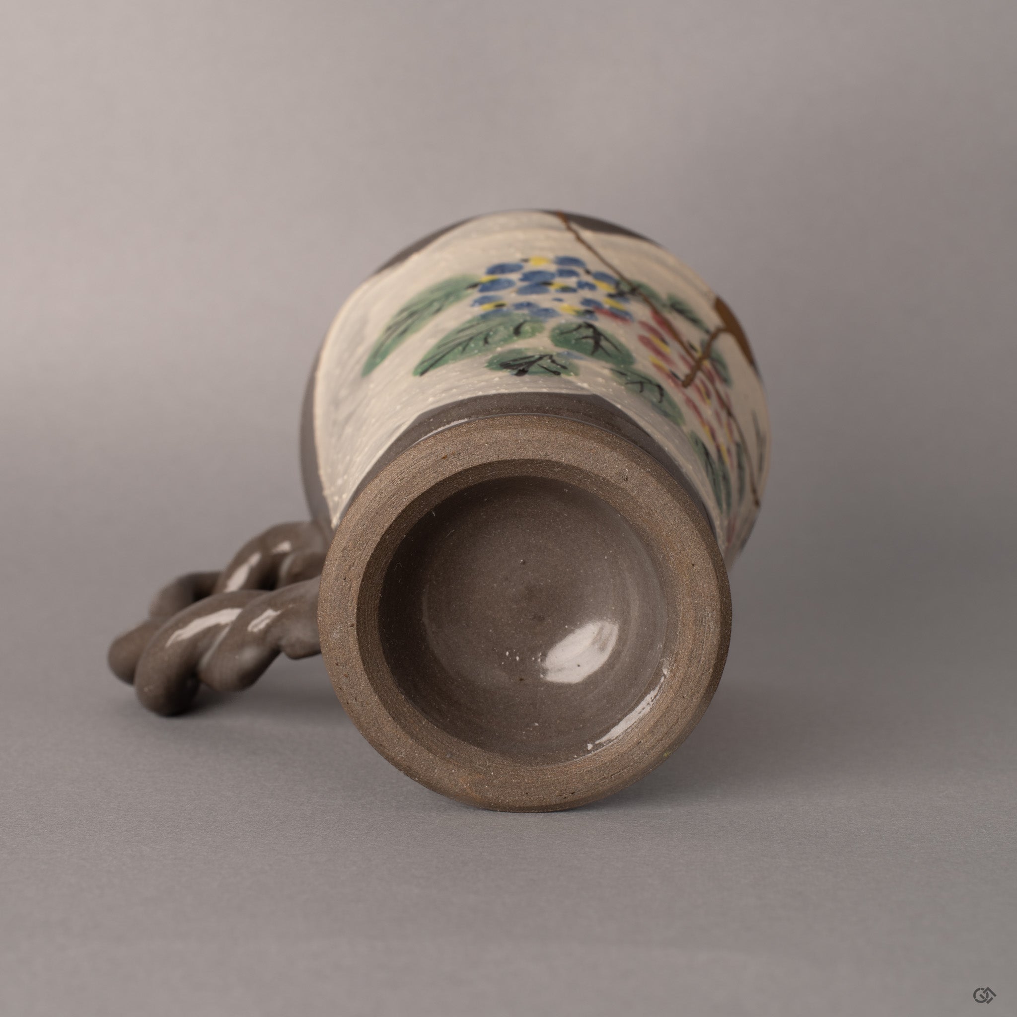The unglazed foot ring reveals the earthenware beneath, grounding this kintsugi mug in centuries of Kyoto ceramic tradition.