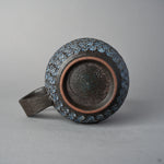 Underside of the Kyoto ware mug showing the unglazed foot ring, dark fired clay with a stamped potter's mark, and white mishima florets circling the body.