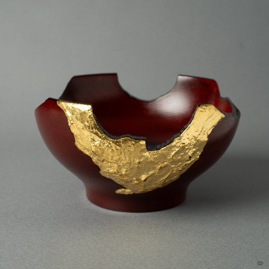 A front view of a rock-like lacquerware piece with gold leaf on a lacquered wooden cup, crafted in the style of wabi-sabi. It exudes wabi-sabi elegance and Japanese artistry.
