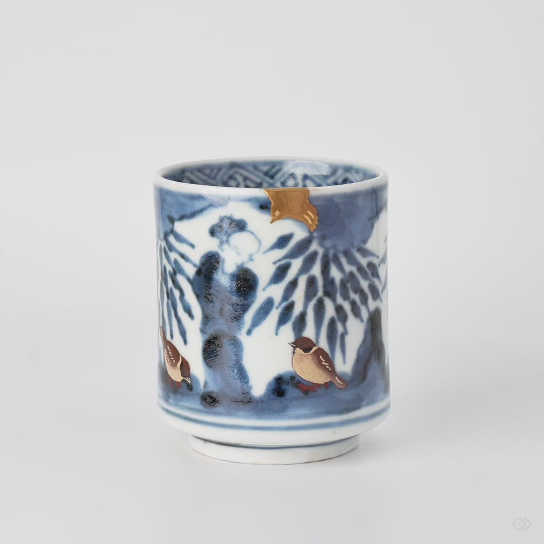 Rotating view of a kintsugi sake cup in Ko-Imari porcelain rebuilt with natural urushi, a 24K gold sparrow at the rim and two urushi-e sparrows below.