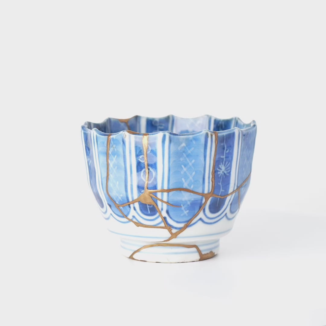 Rotating view of a Ko-Imari sake cup in blue-and-white porcelain with 24K gold kintsugi seams, turning to show the full restoration.