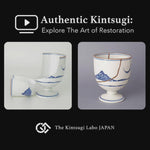A lacquer artist restoring an Arita ware sake cup in white porcelain with 100% natural urushi and 24K gold, showing the kintsugi restoration process in the studio.