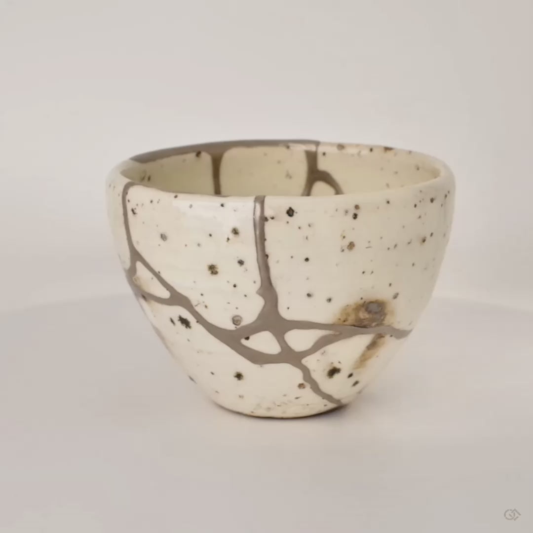 360-degree rotation of silver kintsugi Shigaraki cup revealing branching seams from every angle, living philosophy.