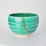 Rotation video of a kintsugi matcha bowl in Kyoto ware, the urushi and 24K gold seam circling the emerald crackle glaze.