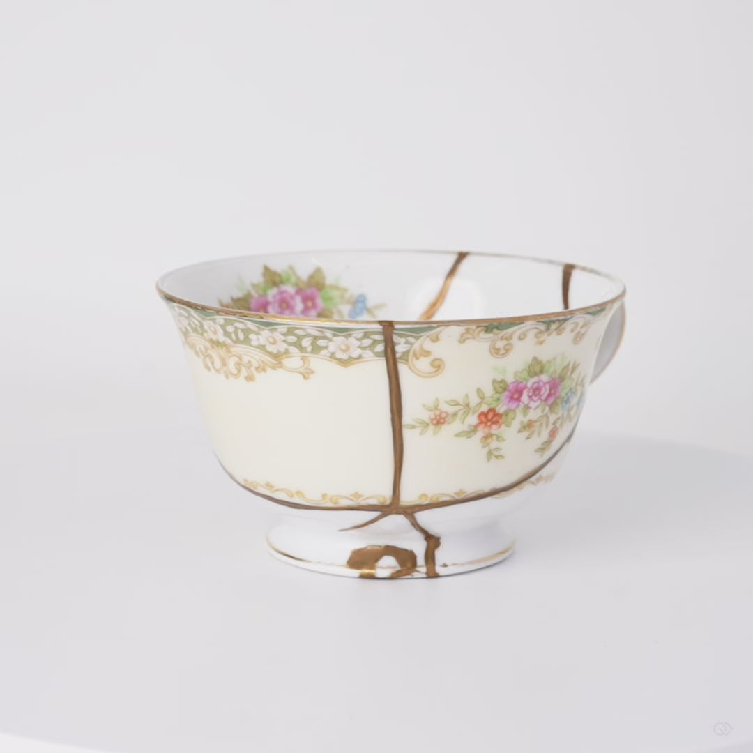 Rotating view of a kintsugi tea cup in cream Early Noritake porcelain with natural urushi and 24K gold seams, turning to show the full restoration.