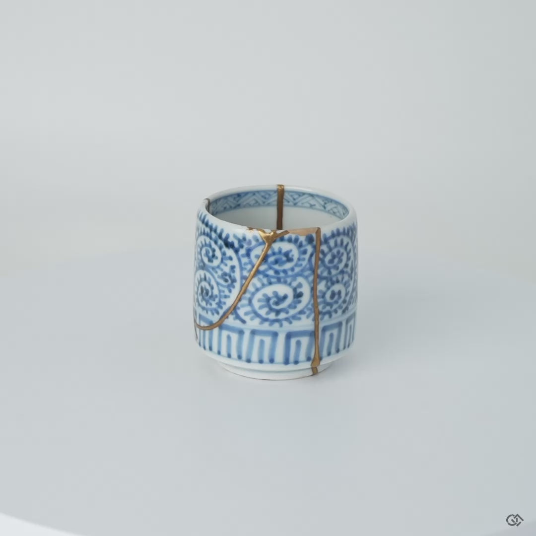 Rotating view of a Ko-Imari sake cup in blue takokarakusa porcelain with 24K gold kintsugi seams, restored with natural urushi, turning to show the full restoration.
