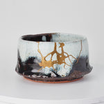 Rotating view of a Karatsu ware matcha bowl in white and black glaze with natural urushi and 24K gold kintsugi seams, turning to show the full restoration.