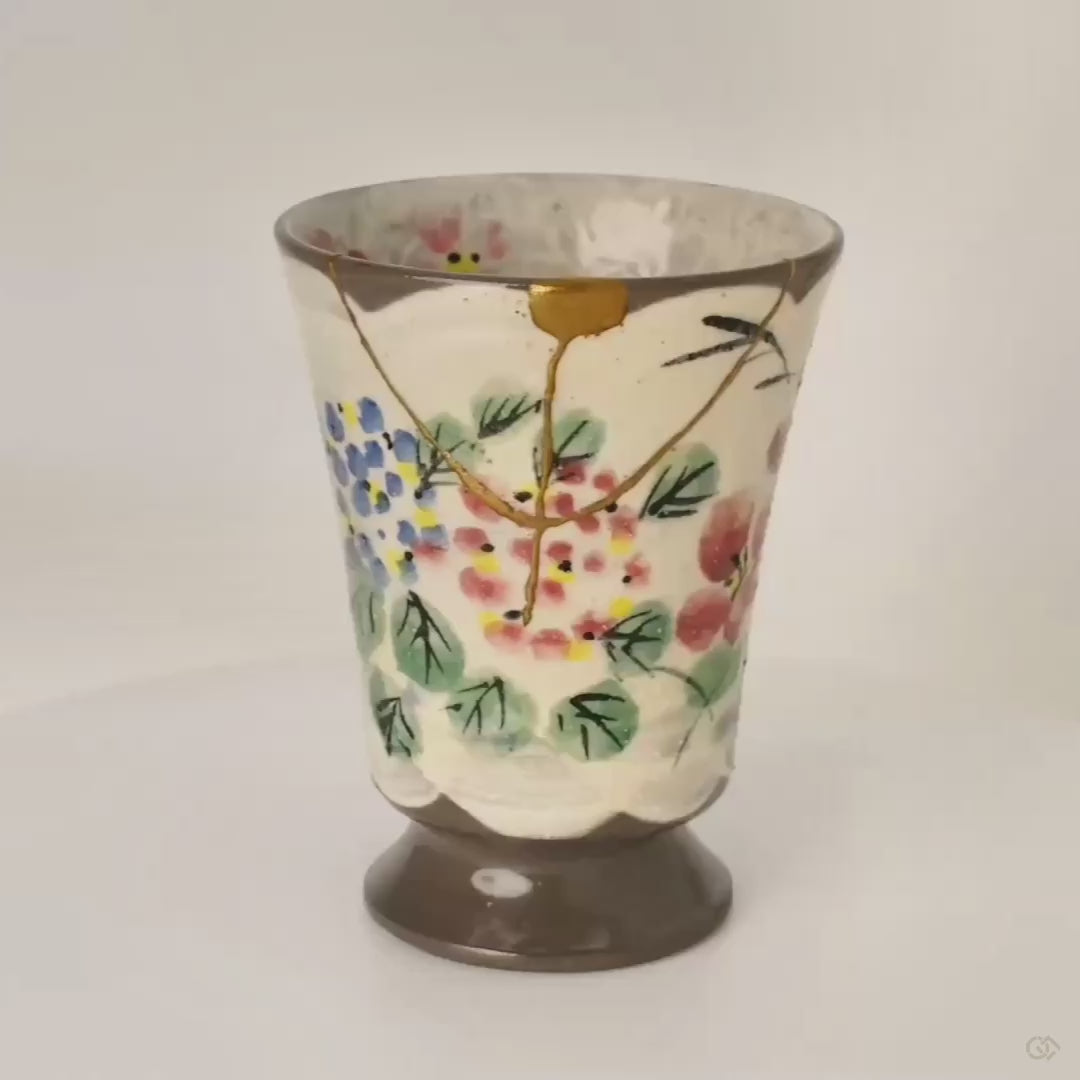 The Kyoto mug turns slowly, revealing gold kintsugi lines winding through painted florals, a soulful object in motion.
