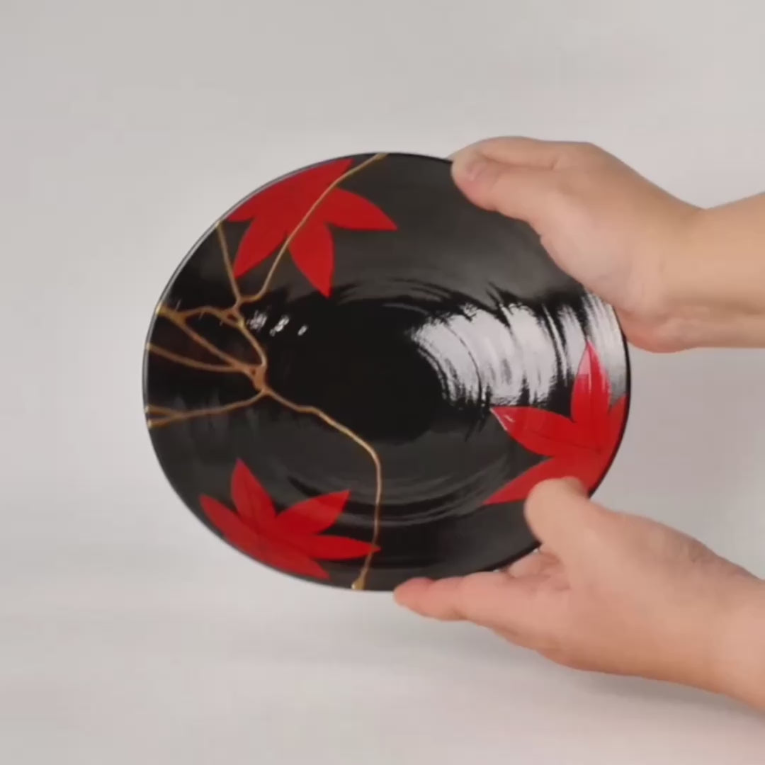 Hands gently turning an Arita ware kintsugi bowl to reveal its dual nature—24K gold restoration on the surface, vermillion iro-urushitsugi on the reverse—two faces of beauty held in one vessel.