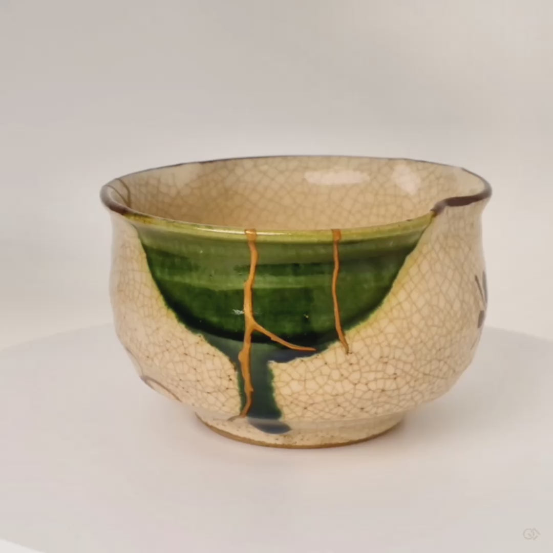 360-degree rotation of a kintsugi Oribe matcha bowl, gold lines catching the light as crackled glaze and copper-green turn slowly, philosophy in form.
