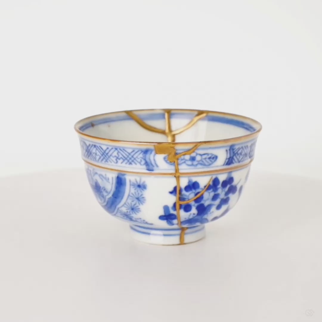360-degree rotation of kintsugi Ko-Imari cup, gold lines turning through hand-painted blue panels, timeless elegance in motion.