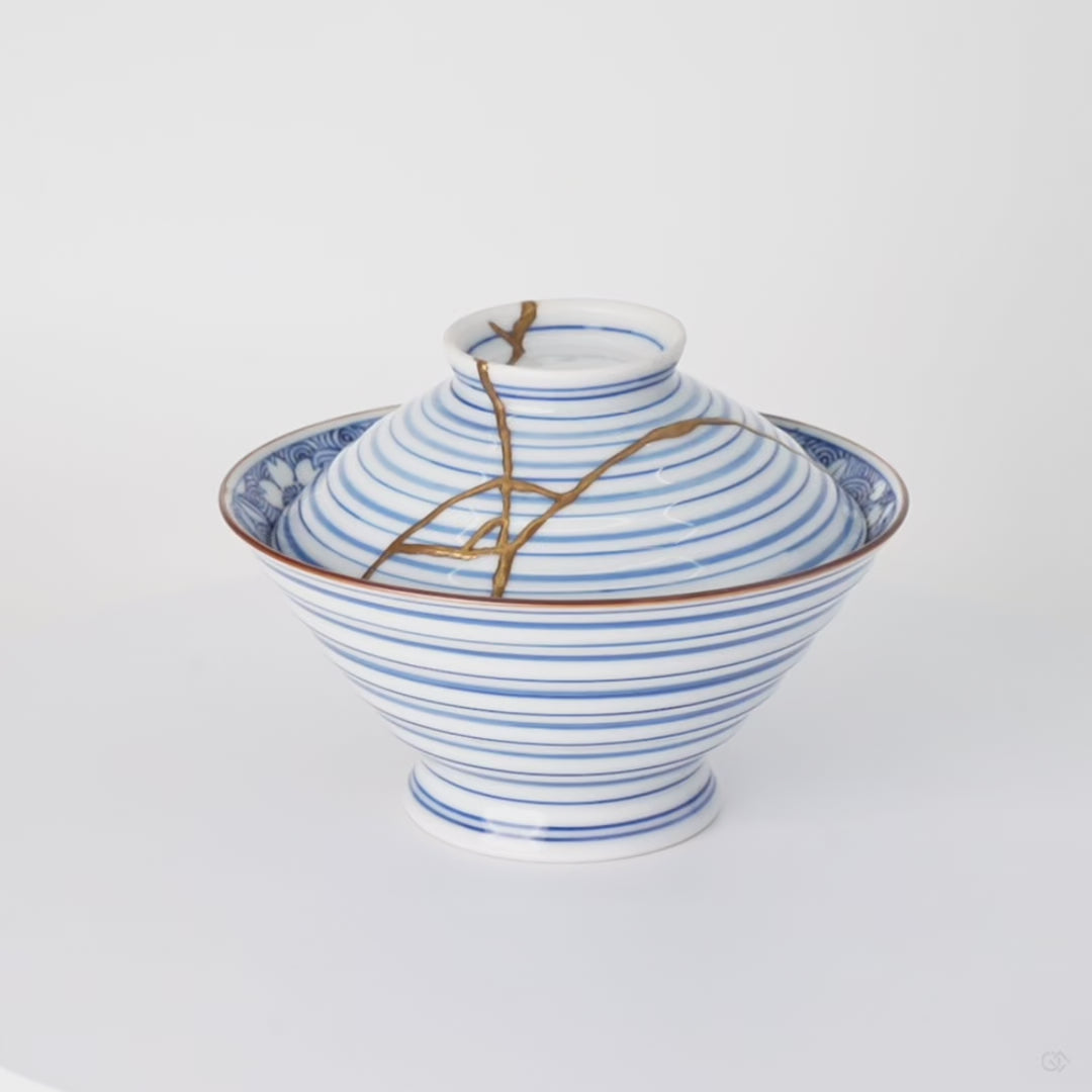 Rotation video of a kintsugi bowl with lid in Arita porcelain, natural urushi and 24K gold lines turning across the blue rings of the lid.