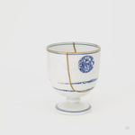 Rotating view of an Arita ware sake cup in white porcelain, cobalt-blue sometsuke bands and 24K gold kintsugi seams turning to show the full restoration.