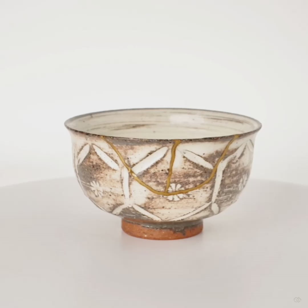 360-degree rotation of a kintsugi Kyoto ware cup revealing gold seams from every angle, slow craft visible in continuous motion.