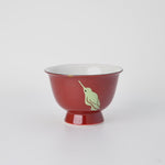 Rotating view of a Kyoto ware sake cup in red porcelain with a 24K gold kintsugi point and urushi-e hummingbirds, turning to show the full restoration.