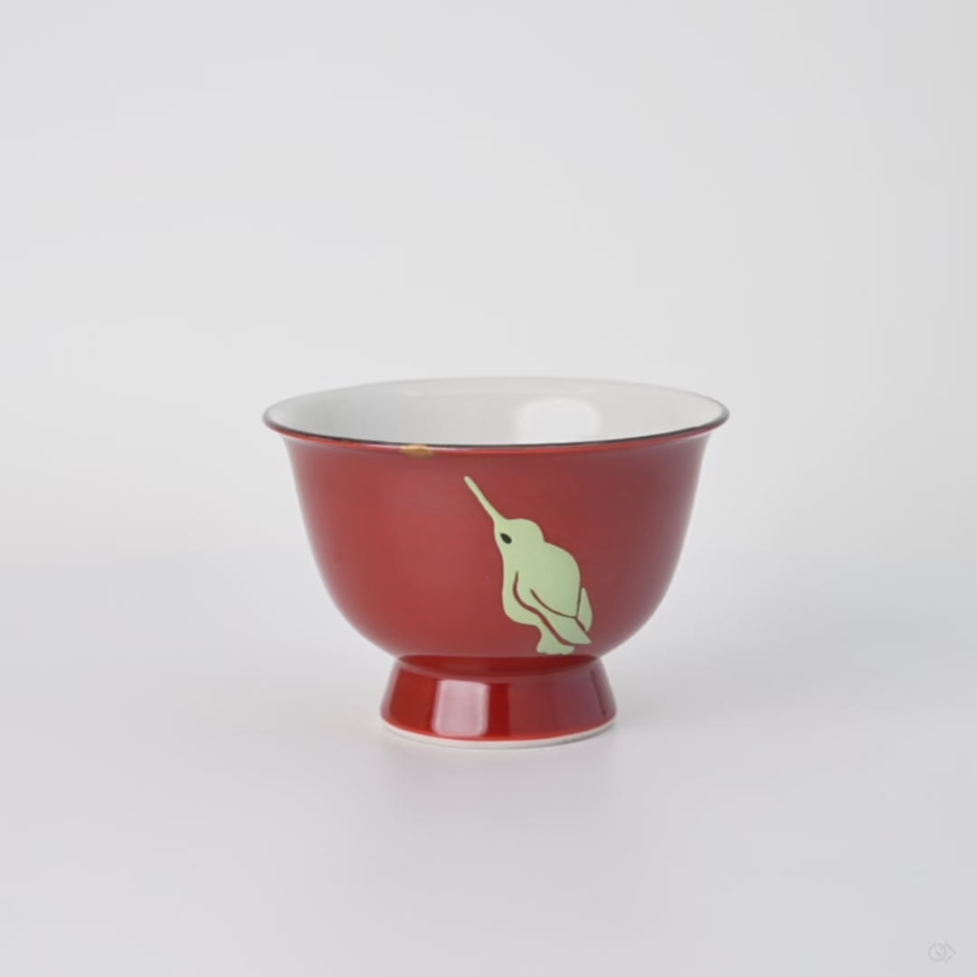 Rotating view of a Kyoto ware sake cup in red porcelain with a 24K gold kintsugi point and urushi-e hummingbirds, turning to show the full restoration.