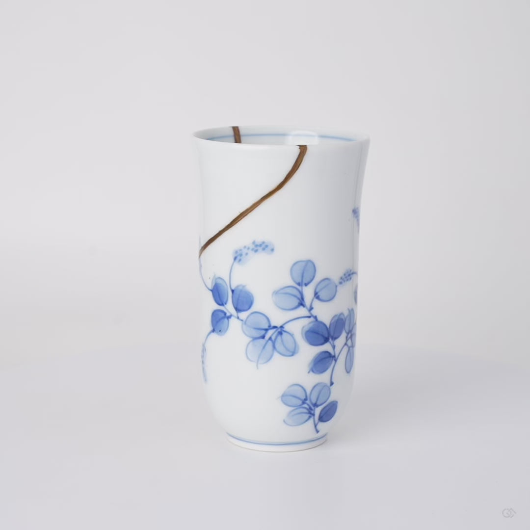 Rotating view of a kintsugi sake cup in thin Arita sometsuke porcelain, restored with natural urushi and finished in 24K gold, turning to show the full seam.