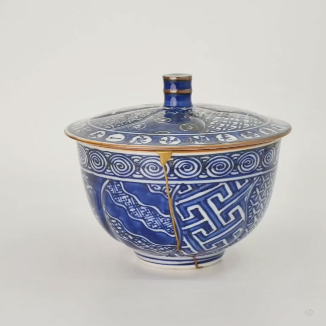 Rotating view of a Kyoto ware kintsugi cup, sometsuke cobalt blue Uzu-komon patterning, single continuous 24K gold seam, fitted lid with gold knob.