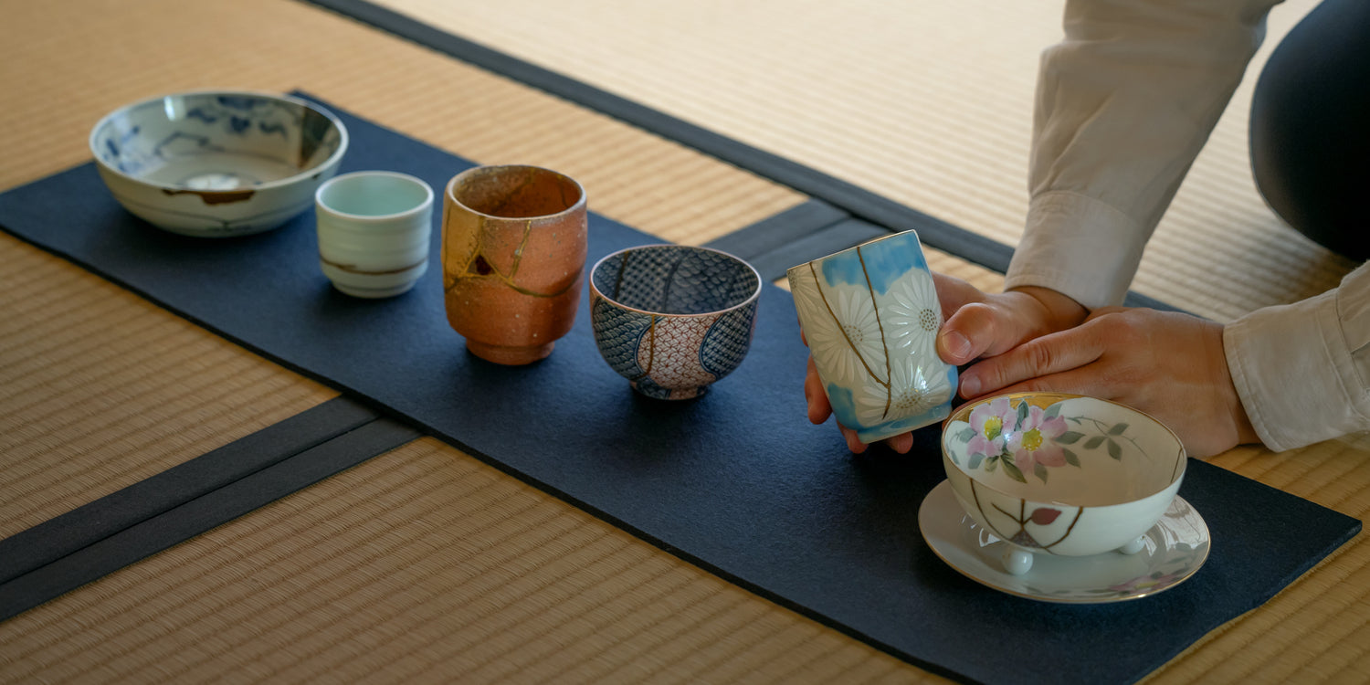 A guest inspecting a Kintsugi masterpiece up close, chosen from a curated collection laid out on traditional tatami mats during a private viewing at our Shiga gallery.