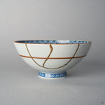 Front view of a Kyoto ware white porcelain rice bowl with red accent lines, a branching 24K gold kintsugi seam descending across the exterior glaze.