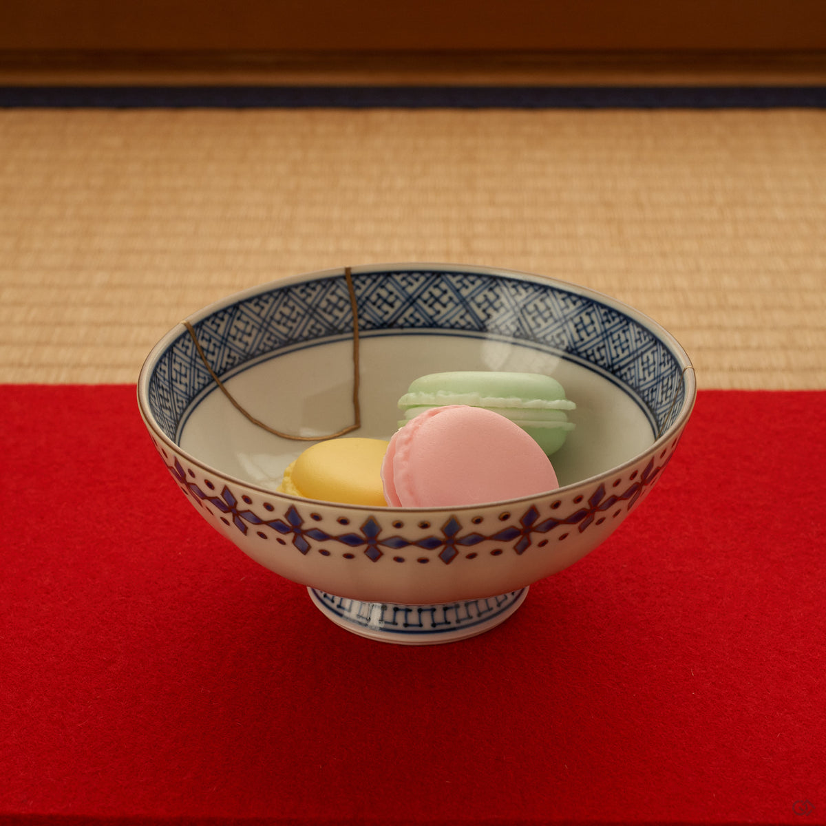 The kintsugi rice bowl rests on tatami in soft daylight, its gold seams and sometsuke blue quiet against the woven mat, conscious luxury at the table.