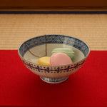 The kintsugi rice bowl rests on tatami in soft daylight, its gold seams and sometsuke blue quiet against the woven mat, conscious luxury at the table.