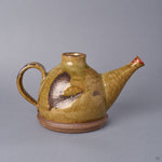 Kyoto ware earthenware sake carafe in ochre Oribe-green crackle glaze, looped handle and long spout, a plum blossom restored at the spout tip in 24K gold with a silver heart, front view.