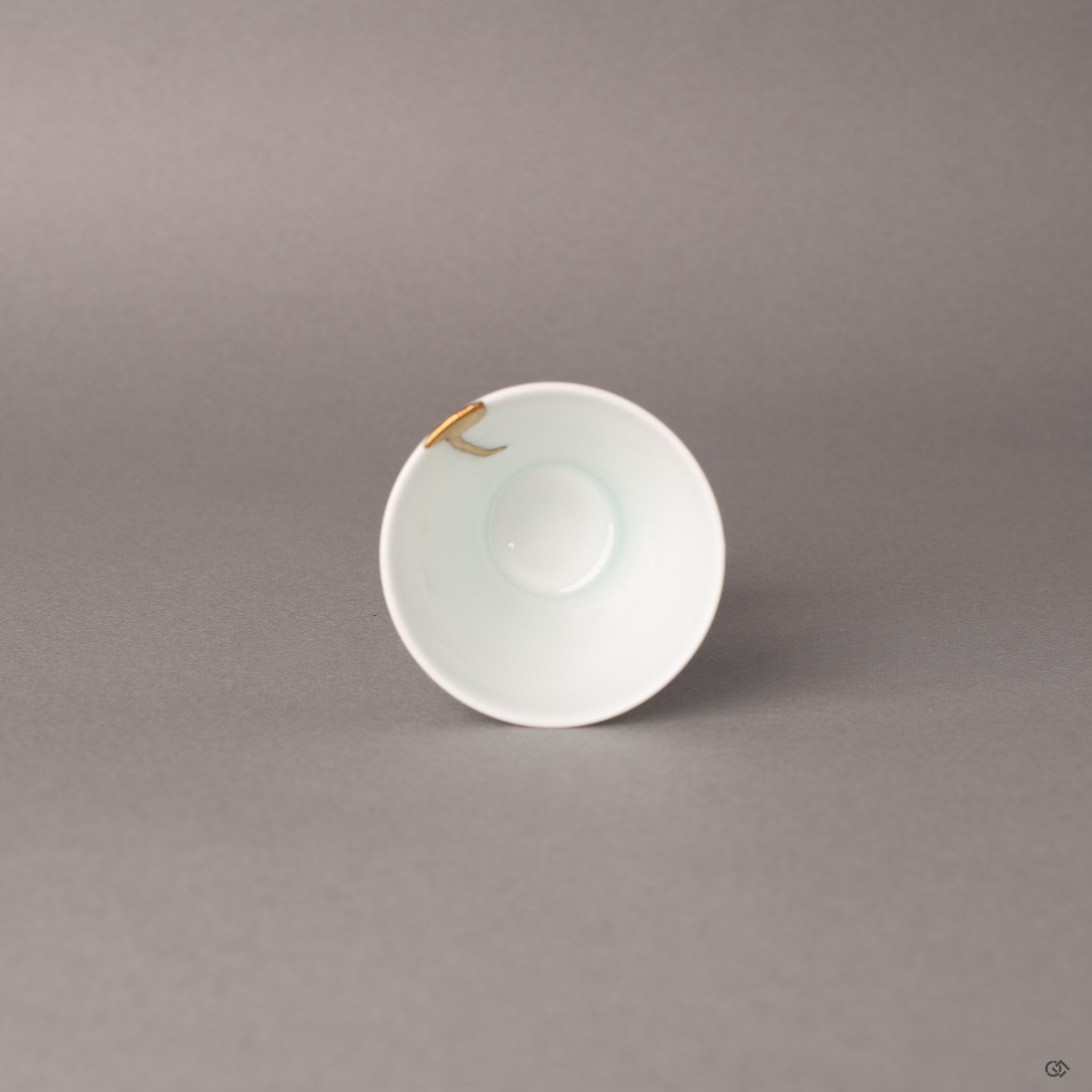 Top view of a kintsugi Ko-Imari sake cup, 24K gold line crossing cobalt blue rim, a philosophy in form.