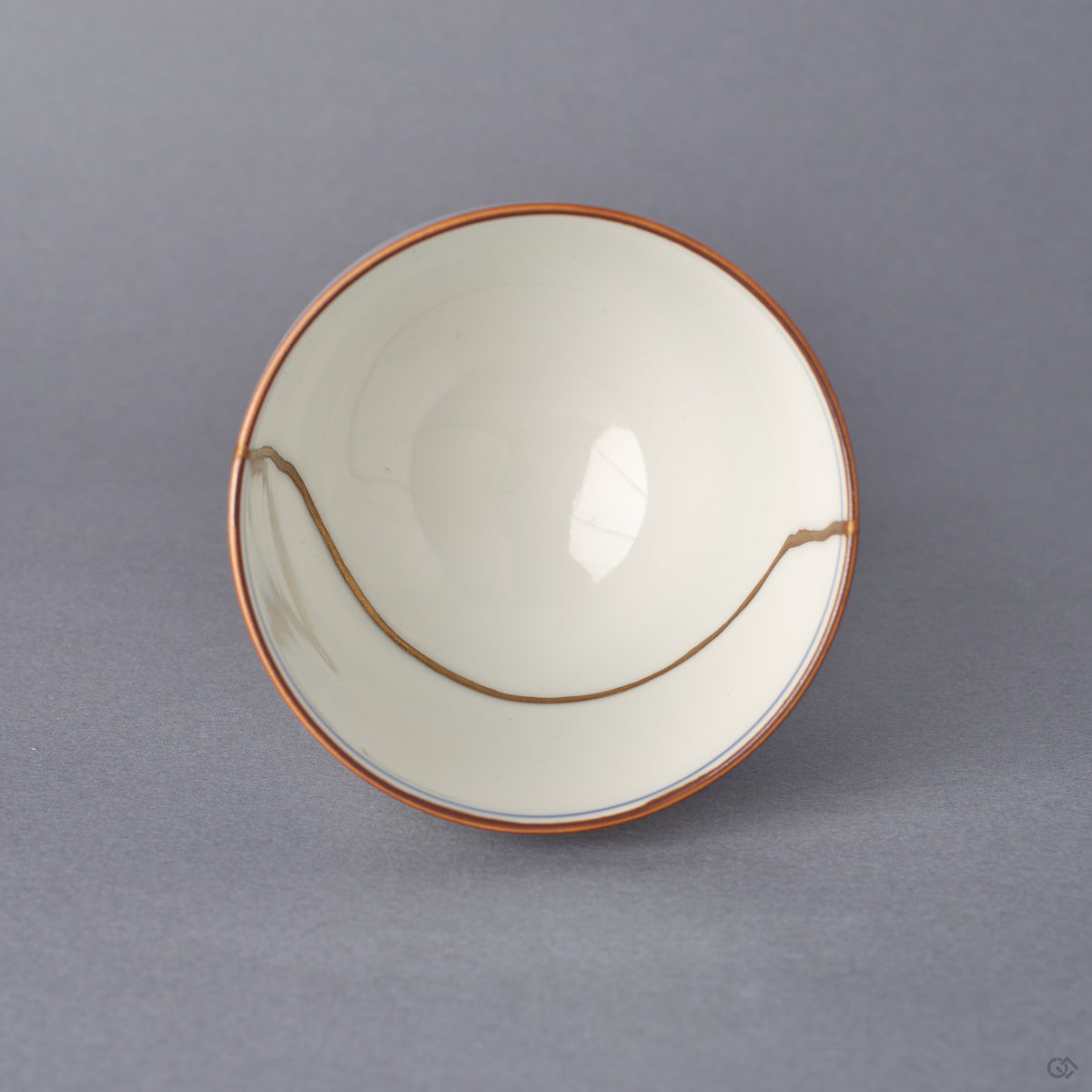 Top-down view into the Arita ware sake cup, a sweeping 24K gold kintsugi seam arcing across the white porcelain interior within an iron-brown rim line.