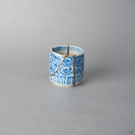 Front view of a Ko-Imari sake cup in sometsuke blue takokarakusa porcelain, 24K gold kintsugi lines rising from foot to rim through the scrolling vines, restored with natural urushi.