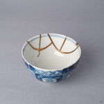 Interior close-up of a Ko-Imari sake cup, two 24K gold kintsugi arcs meeting inside the white glazed wall just below the blue rim line, restored with natural urushi.