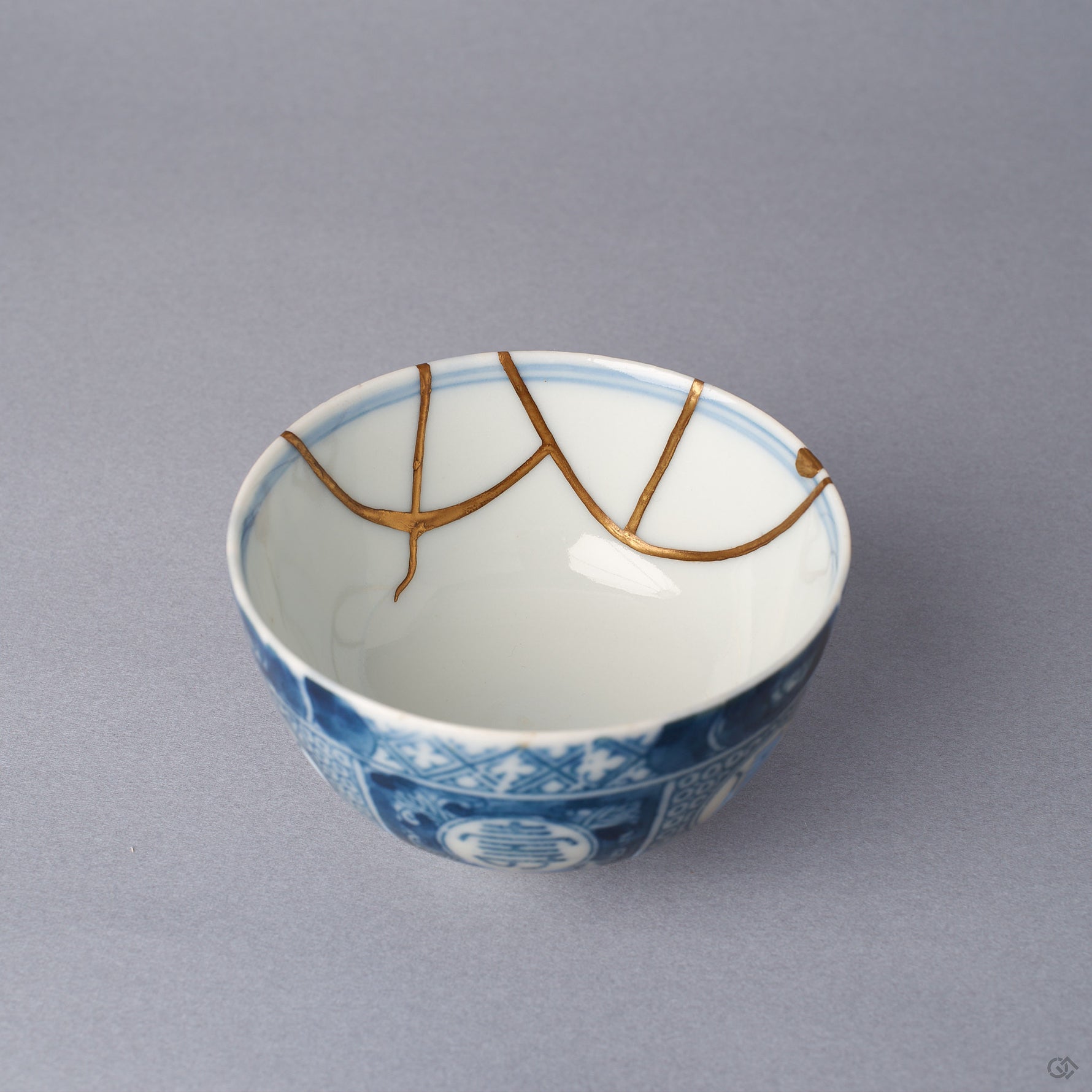 Interior close-up of a Ko-Imari sake cup, two 24K gold kintsugi arcs meeting inside the white glazed wall just below the blue rim line, restored with natural urushi.